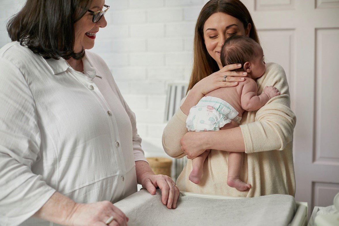 Mum holding baby wearing Huggies newborn nappies with Midwife Cath