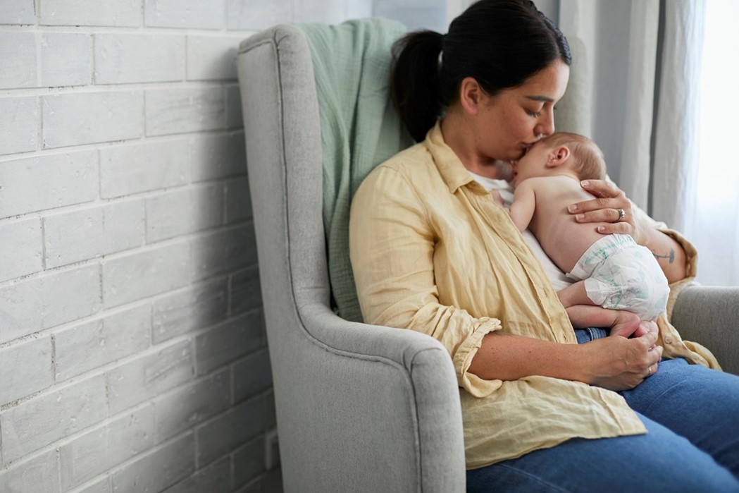 Baby wearing Huggies newborn nappies lying on mum